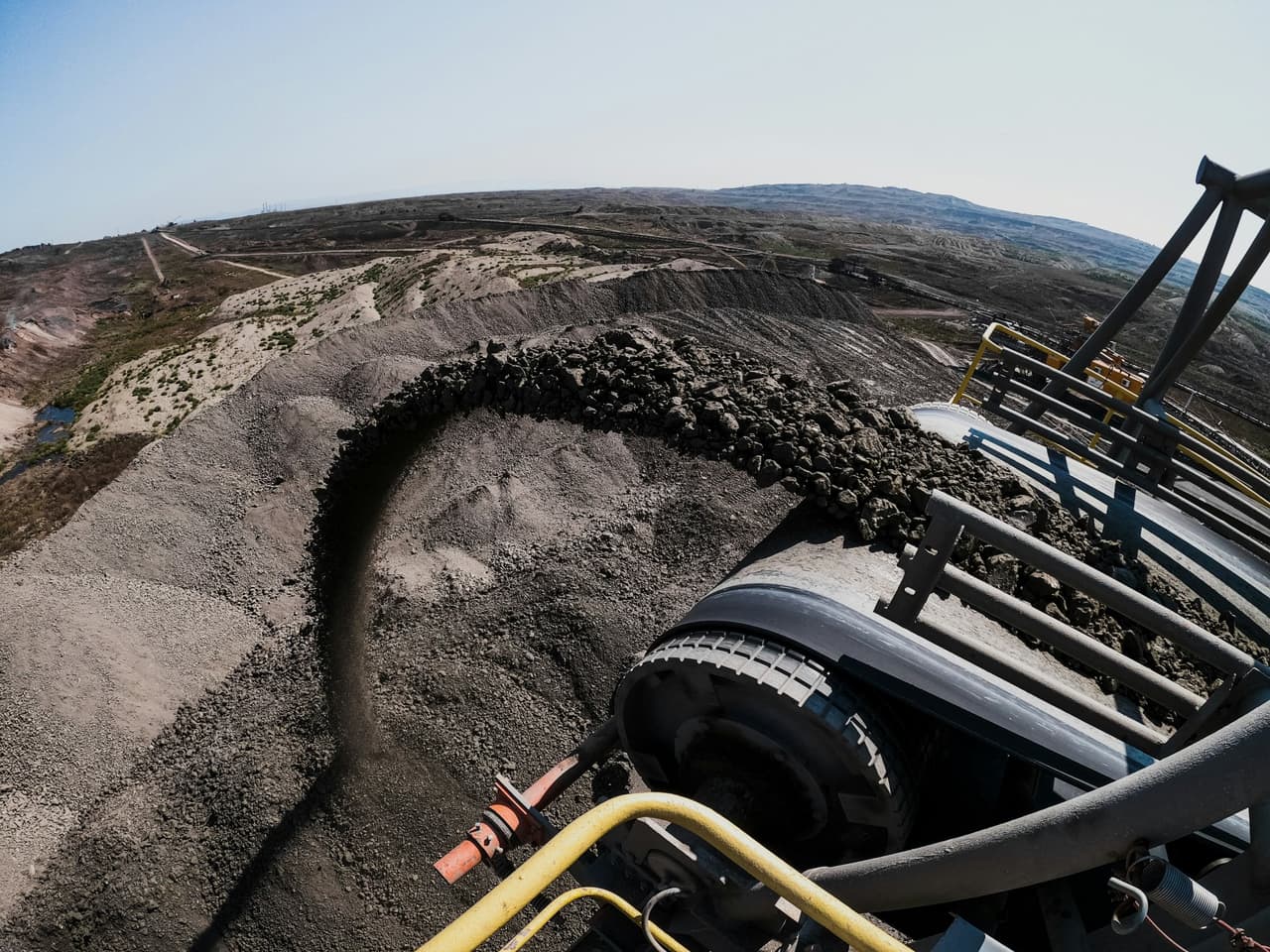 Wide-angle view of a conveyor belt carrying crushed rock at a quarry