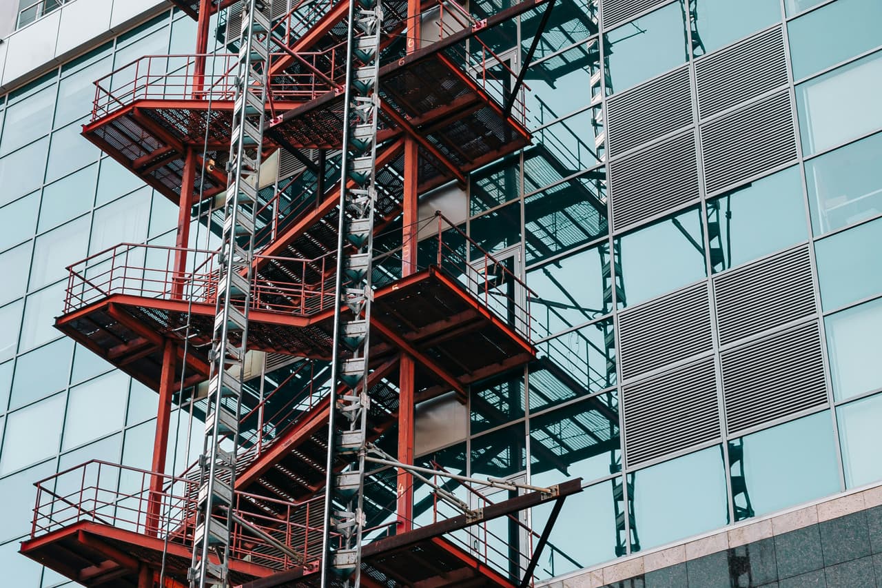Red steel access stairs and landings on a glass-fronted building