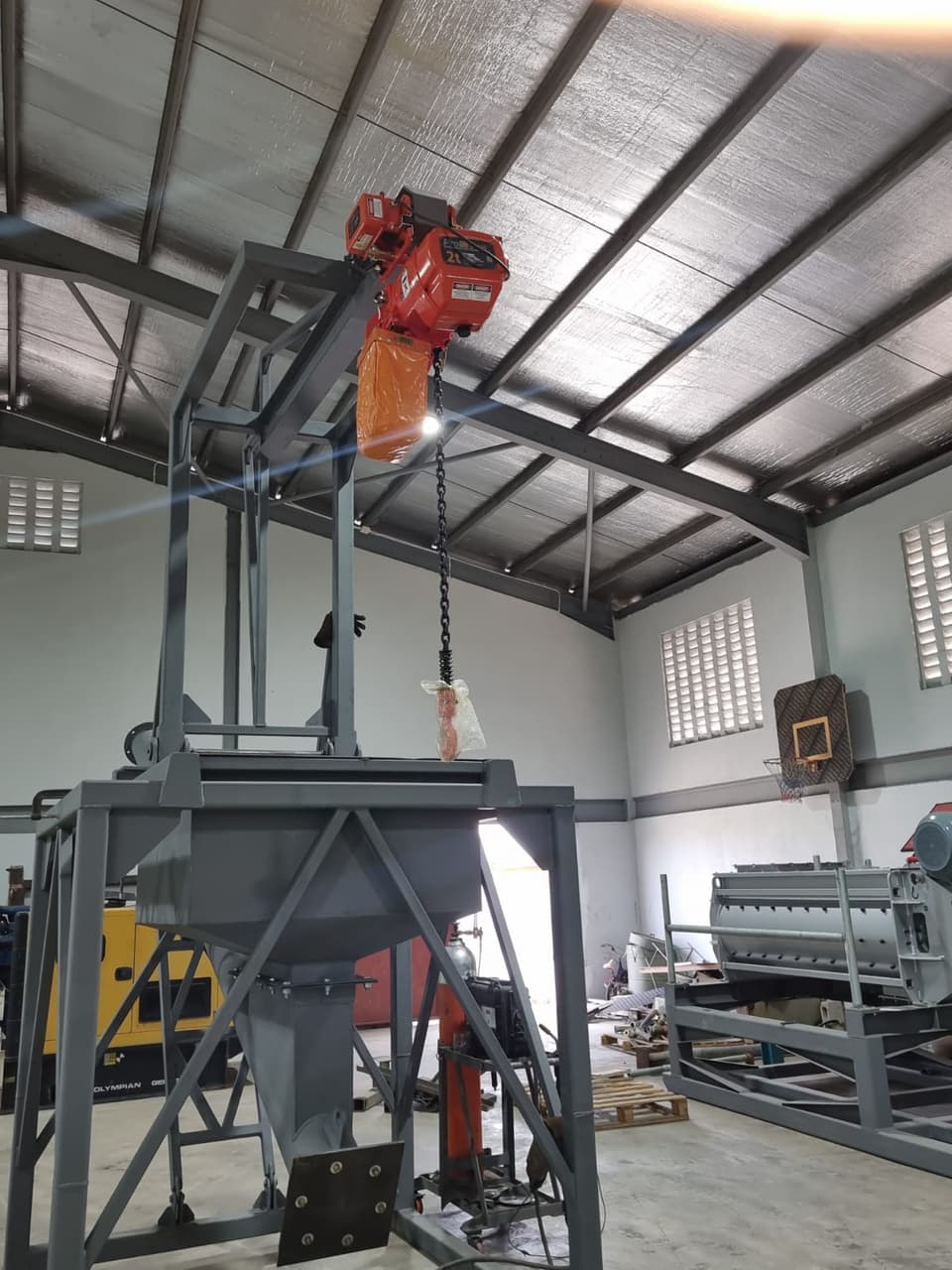 Fabricated steel hopper frame beneath a chain hoist inside a building